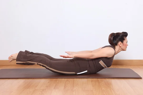 Kvinnan gör yoga övning kallas shalabha-asana — Stockfoto