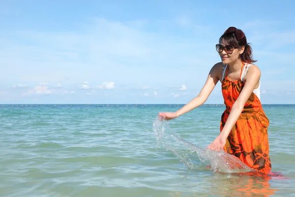 Beautiful young girl splashing the water in the sea — Stock Photo, Image