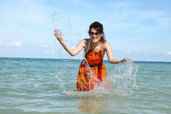 Beautiful young girl splashing the water in the sea — Stock Photo, Image