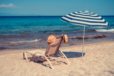 bir şapka ve bir şemsiye güneşli bir plaj sandalyesi