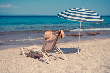 bir şapka ve bir şemsiye güneşli bir plaj sandalyesi