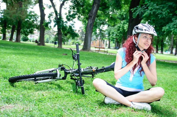 Vacker rödhårig flicka ridning och cykling cykel i en park — Stockfoto