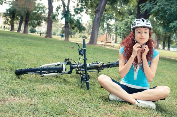 Beautiful redhead girl riding and cycling a bike in a city park — Stock Photo, Image