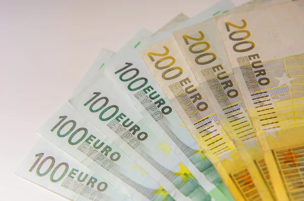 Euros, cien, doscientos y monedas en una mesa blanca — Foto de Stock
