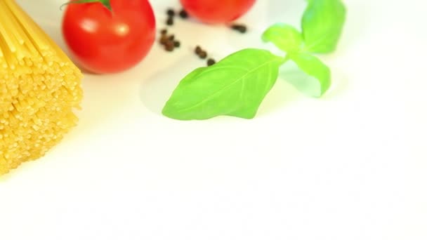 Ingredientes de comida italiana em fundo branco, tomate com macarrão espaguete, alho e manjericão — Vídeo de Stock