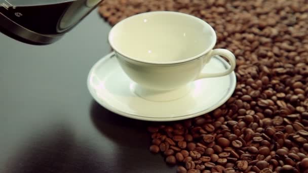 Pouring fresh hot coffee, white cup on coffee beans background — Stock Video