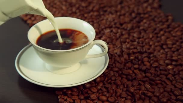 Gieten van melk in een witte kop met verse hete koffie — Stockvideo