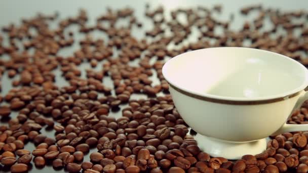 Taze sıcak kahve, kahve çekirdekleri zemin üzerine beyaz fincan dökme — Stok video
