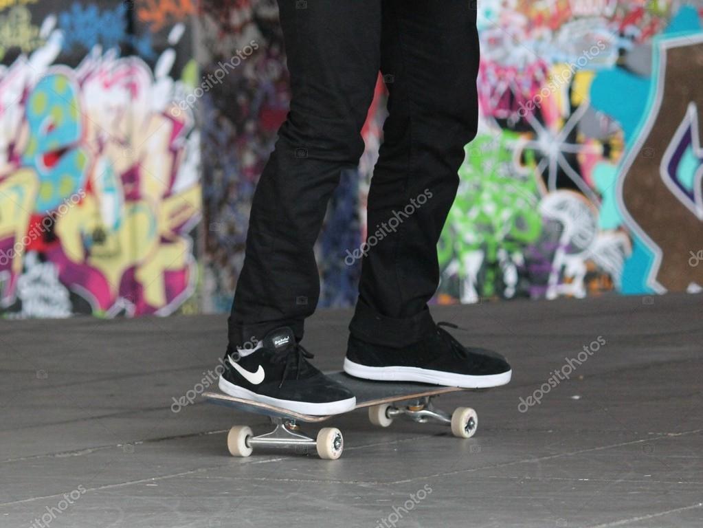 Skateboard at skate park Teenager skater and skateboard legs in skate park with graffiti behind