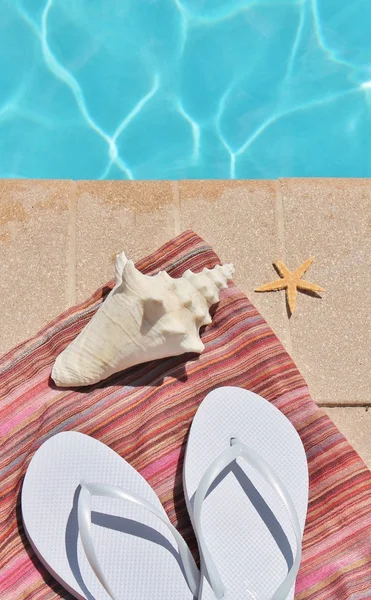 Poolside holiday vacation scenic swimming pool summer shell towel flip flops thongs — Stock Photo, Image