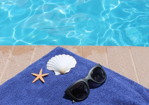 Poolside holiday vacation scenic swimming pool summer sunglasses shell towel starfish — Stock Photo, Image