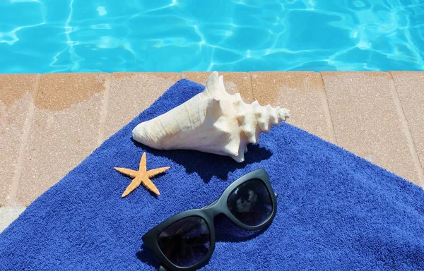 Poolside holiday vacation scenic swimming pool summer sunglasses shell towel starfish — Stock Photo, Image