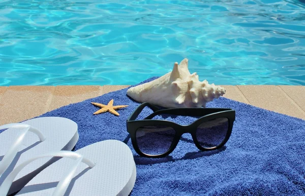 Poolside holiday vacation scenic swimming pool summer sunglasses shell towel — Stock Photo, Image