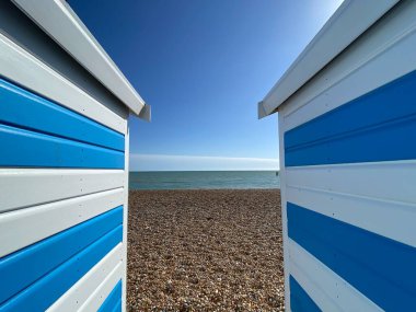 Hastings, Doğu Sussex, İngiltere - 03.15.2022: Yaz günü Hastings sahil kulübeleri çakıl taşı plajındaki güzel mavi çizgili kulübeler