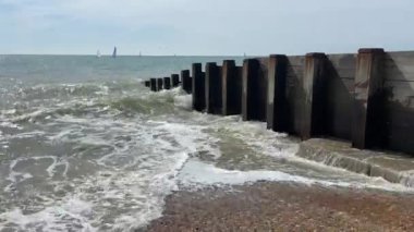 St Leonard, Hastings, Doğu Sussex, İngiltere - popüler yaz plajı, dalgalar yelkenli teknelerle ahşap plaj damızlıklarına çarpıyor - video görüntüleri