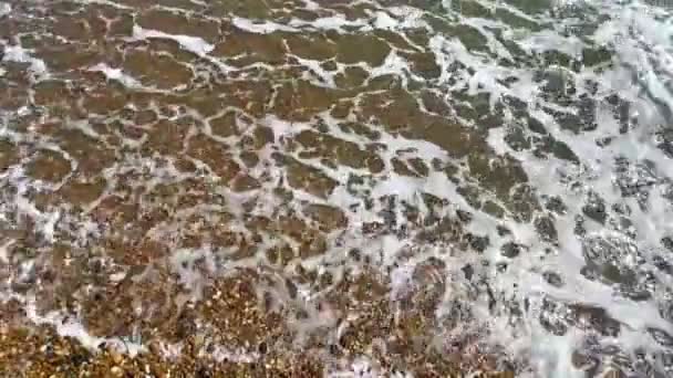 背景波の上から波が打ち寄せる小石の砂浜 — ストック動画
