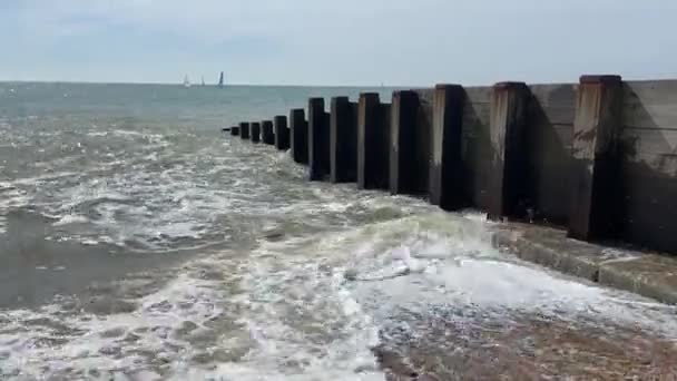 ヘイスティングス イーストサセックス イギリス 人気の夏のビーチ 波が帆ボートで木製のビーチグラインを打つ ビデオ映像 — ストック動画