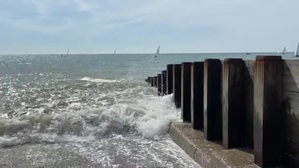 ヘイスティングス イーストサセックス イギリス 人気の夏のビーチ 波が帆ボートで木製のビーチグラインを打つ ビデオ映像 — ストック動画