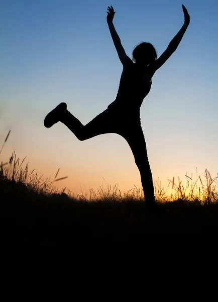 Silhouette of girl jumping in field — Stock Photo, Image