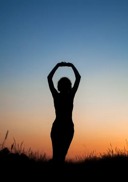 Silueta de chica estirándose en el campo — Foto de Stock