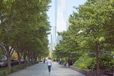New York, NY, USA - July 25, 2022: People walking along the Hudson River Greenway pedestrian path in lower Manhattan with the World Trade Center shown in the background using a shallow depth of field