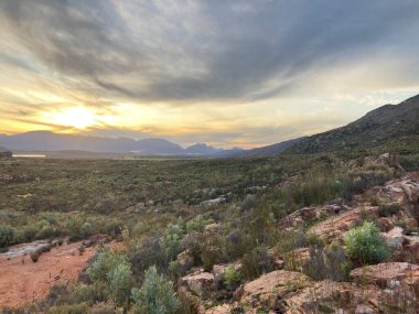 Koue Bokkeveld dağlarının arka planında soğuk ve bulutlu bir kış gününde gün batımının fotoğrafı..