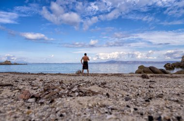 A man staring at the sea, at a secluded beach in Sithonia, Chalkidiki, Greece clipart