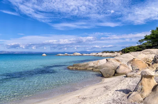 Rochas em uma praia de areia na Sithonia, Chalkidiki, Grécia, com água cristalina — Fotografia de Stock