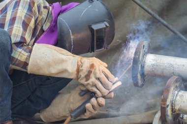 Koruyucu giysiler giyen erkek kaynakçı. Boru hattı dumanını tamir ediyor.