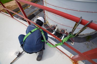 Önce emniyet kemeri ve emniyet kemeri takan erkek işçi. Yüksek korkulukların olduğu yerde çalışıyor.
