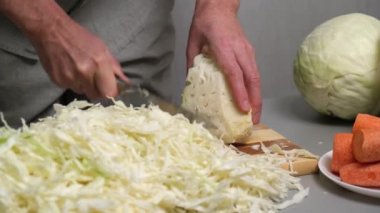 4K erkek aşçı tahta kesme tahtasındaki bıçakla taze lahana kesiyor. Lahananın mayalanması için hazırlık. Düzgün beslenme ve sağlıklı yaşam tarzı kavramı..