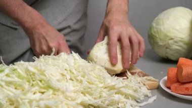 4K erkek aşçı tahta kesme tahtasındaki bıçakla taze lahana kesiyor. Lahananın mayalanması için hazırlık. Düzgün beslenme ve sağlıklı yaşam tarzı kavramı..