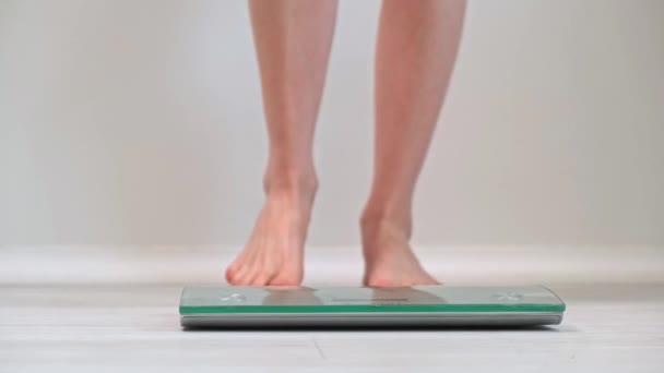 一个小女孩走近并站在天平上测量体重 裸女脚特写 日常体重控制和健康生活方式的概念 日常使用的现代数字刻度 — 图库视频影像