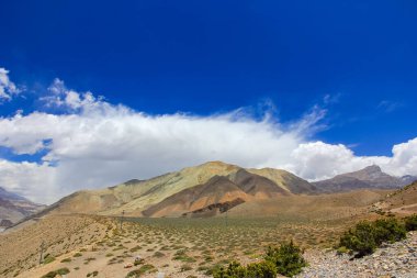 Kahverengi dağlar mavi gökyüzüne karşı beyaz bulutlarla