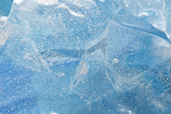 Beautiful natural blue ice block splitted texture with frozen air bulbs closed up