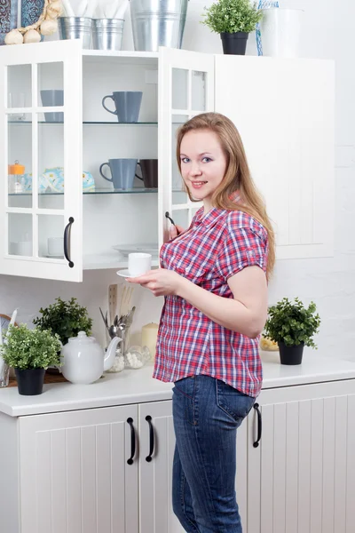 Young woman in kitchen with cup — Stock Photo, Image