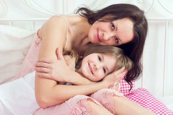 Jovem Mãe e filha abraçando na cama — Fotografia de Stock