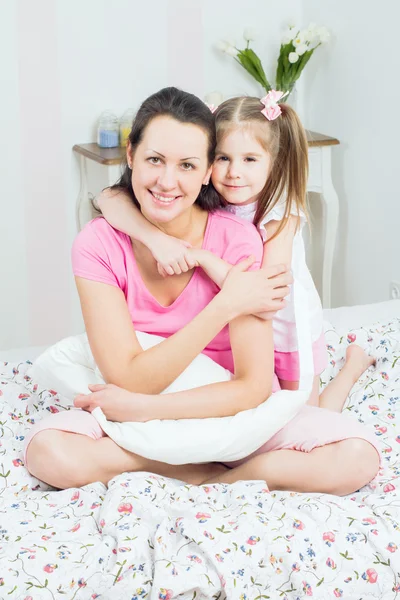 Genç anne ve kızı yatağa kucaklayan — Stok fotoğraf