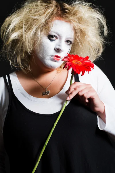 Vrouw pantomime met een rode bloem — Stockfoto