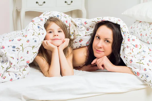 Счастливые мать и дочь лежат на кровати — стоковое фото