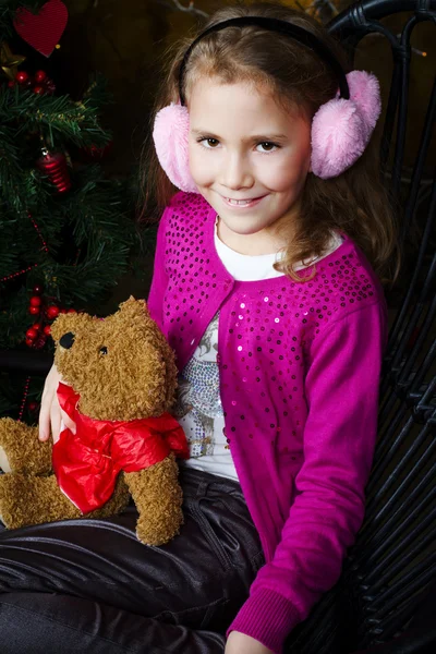 Маленькая девочка сидит рядом с рождественской елкой — стоковое фото