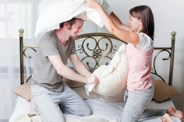 Par som kämpar tillsammans med kuddar i sängen — Stockfoto