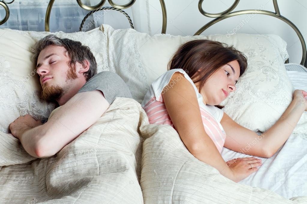Young husband and wife sleeping on the bed in bedroom