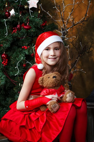 Cute little girl in a red dress near a Christmas tree Royalty Free Stock Photos