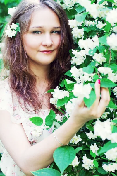 Ung kvinna i en blommande trädgård — Stockfoto