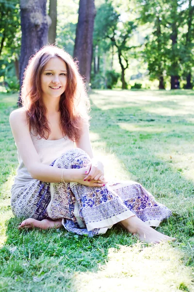 Молодая женщина, сидящая на траве — стоковое фото
