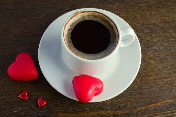 Tasse schwarzen Kaffee, zwei rote Marzipan-Bonbons — Stockfoto