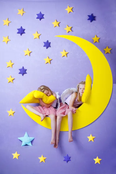 büyük bir ayda oturan iki sevimli kız