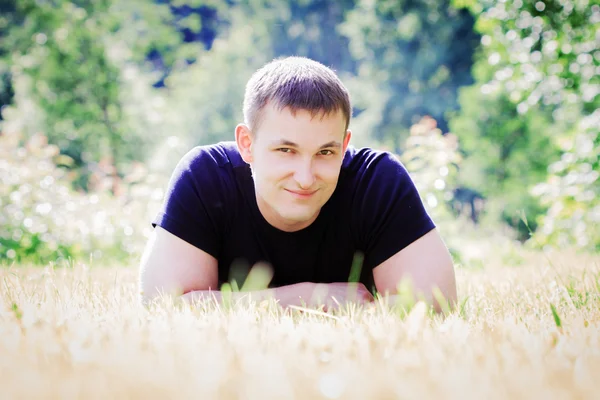 年轻男子在公园草地上的谎言 — 图库照片