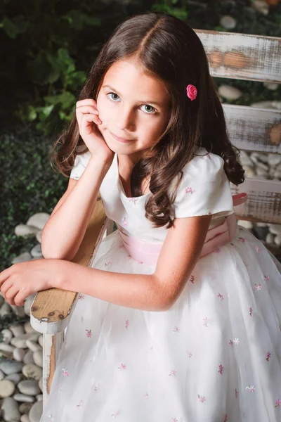 Portrait of a cute little girl sitting in the flowered garden — Stock Photo, Image